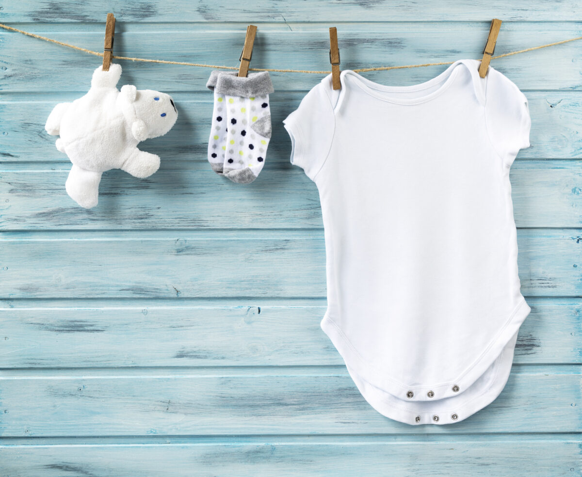 Baby boy clothes and white bear toy on a clothesline